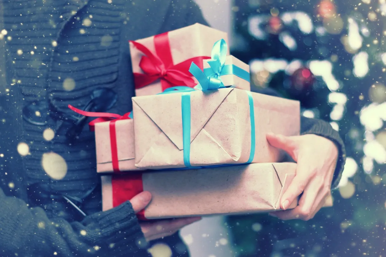 Person holding wrapped gifts in snowfall