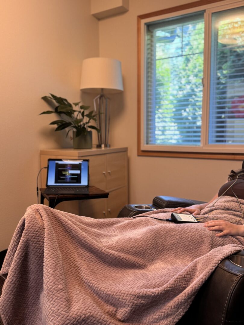 Person reclining under pink blanket with laptop