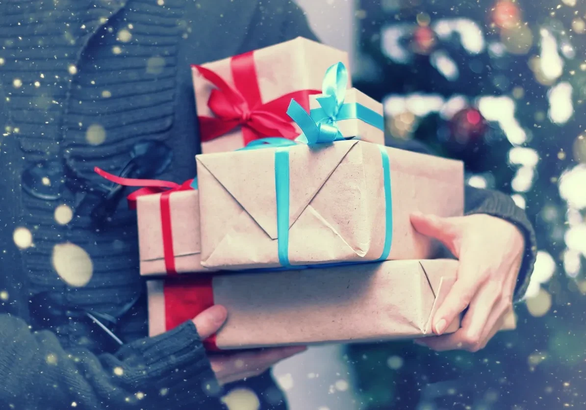 Person holding wrapped gifts in snowfall